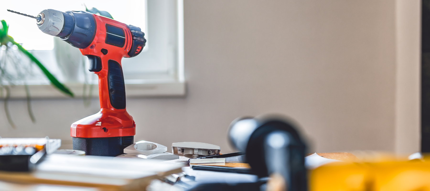 A red power drill surrounded by tools and supplies