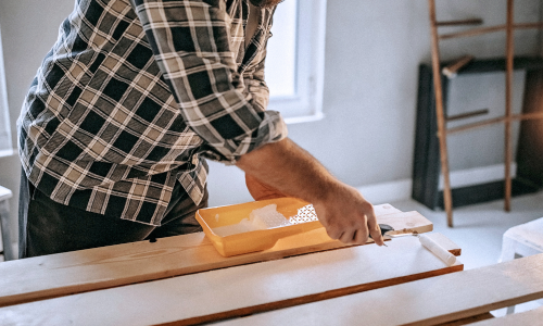 Man painting wood with a roller