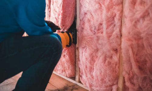 Pink insulation being installed on a wall