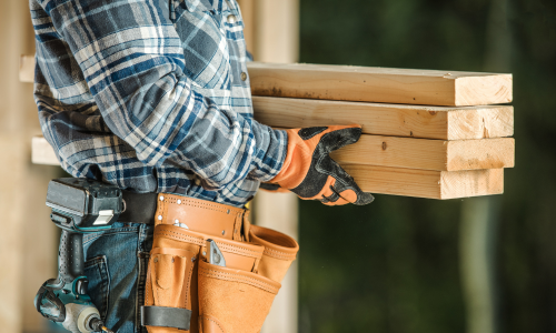 A contractor carrying lumber