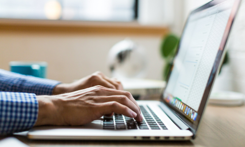 Hands typing on a laptop keyboard