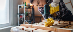 Woman using a power drill to screw in wood framing